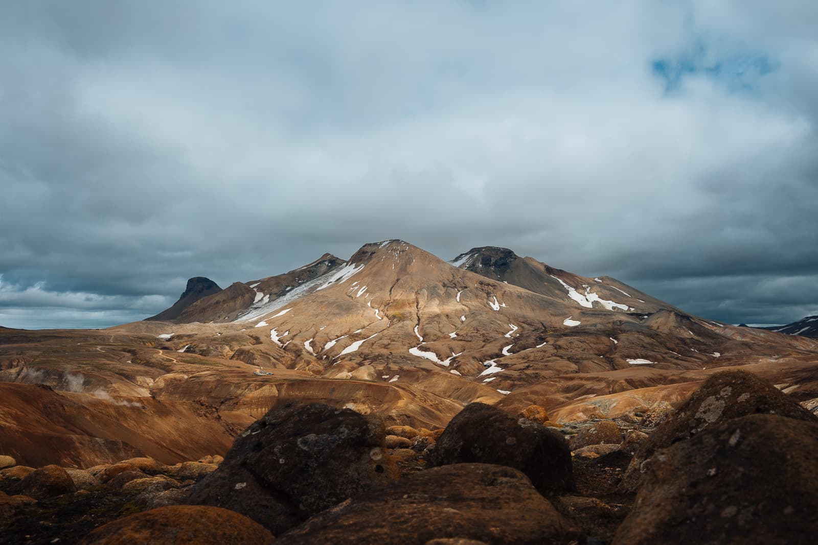 Rust-colored ridges and snow patches in the Icelandic highlands beneath low clouds