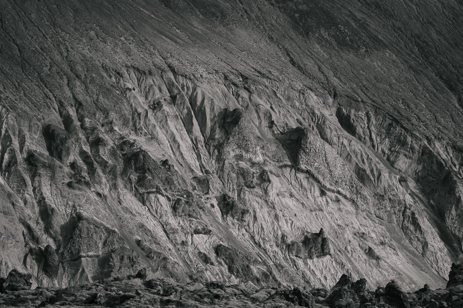 Close-up of fine erosion channels and jagged ridges on a gray volcanic slope in Iceland
