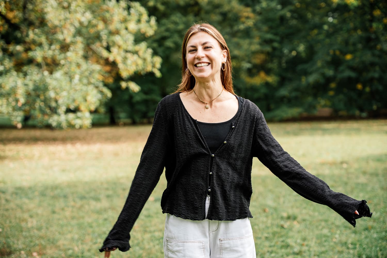 Laughing woman with outstretched arms during a portrait session in a park